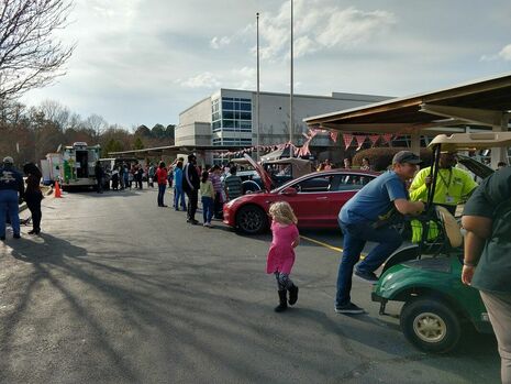 People stand in front of cars at Drew Charter Elementary School as part of DESIGNORAMA.